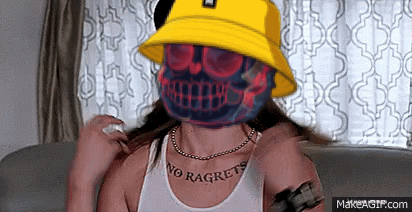 A Woman Wearing A Yellow Bucket Hat Has A Skull On Her Face GIF