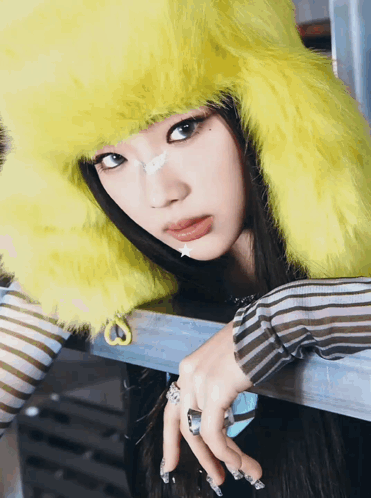 A Woman Wearing A Yellow Furry Hat And Striped Shirt GIF