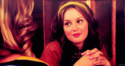 A Woman Wearing A Yellow Headband Is Smiling And Looking At Another Woman GIF