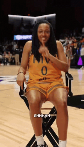 A Woman Wearing A Yellow Jersey With The Number 0 On It Sits In A Chair GIF
