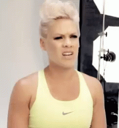 A Woman Wearing A Yellow Nike Sports Bra Is Making A Funny Face . GIF