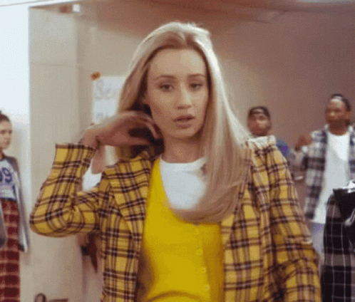 A Woman Wearing A Yellow Plaid Jacket And A Yellow Sweater With The Number 99 On It GIF