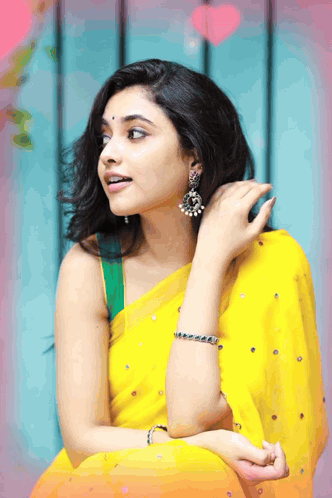 A Woman Wearing A Yellow Saree And Earrings Is Looking To The Side GIF