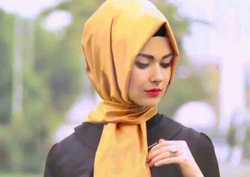 A Woman Wearing A Yellow Scarf And A Black Shirt GIF