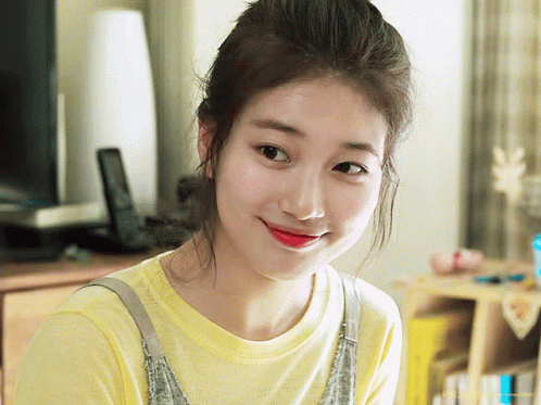 A Woman Wearing A Yellow T-Shirt And Overalls Smiles For The Camera GIF