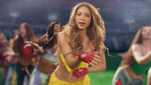 a woman wearing a yellow top and red gloves is dancing
