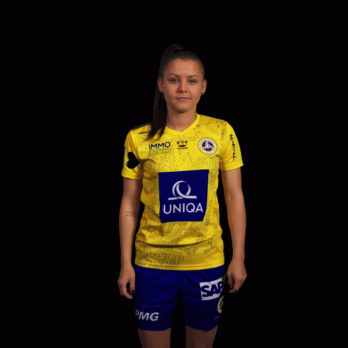A Woman Wearing A Yellow Uniqa Shirt And Blue Shorts GIF