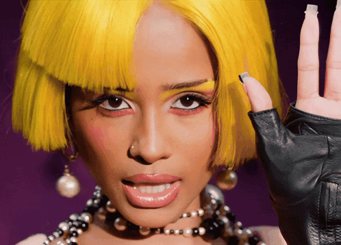 A Woman Wearing A Yellow Wig And A Black Glove GIF