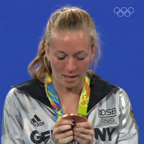 A Woman Wearing An Adidas Jacket Holds A Medal GIF
