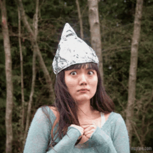 A Woman Wearing An Aluminum Foil Hat Looks Surprised GIF