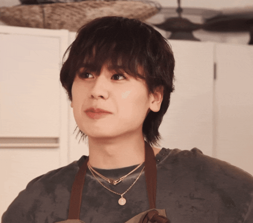 A Woman Wearing An Apron And A Necklace With The Letter A On It GIF