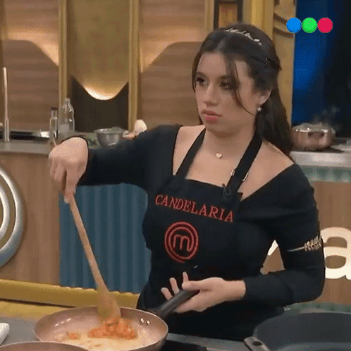 A Woman Wearing An Apron That Says Candelaria Is Stirring Food In A Frying Pan GIF