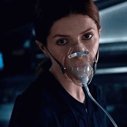A Woman Wearing An Oxygen Mask Is Looking Down At Something . GIF