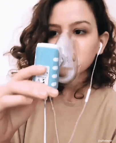 A Woman Wearing An Oxygen Mask Is Taking A Selfie With Her Phone GIF