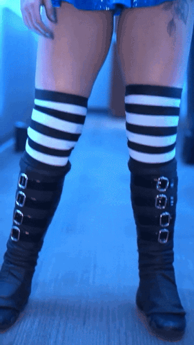 A Woman Wearing Black And White Striped Thigh High Socks GIF