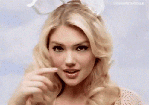 A Woman Wearing Bunny Ears Is Making A Funny Face With Her Finger . GIF