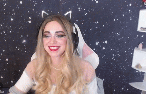 A Woman Wearing Cat Ears And Headphones Is Smiling In Front Of A Starry Background . GIF