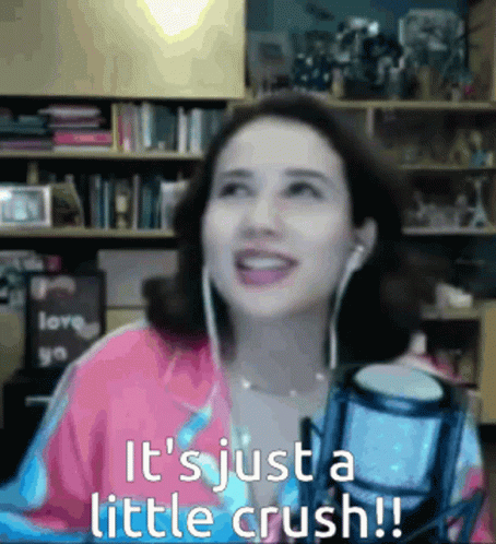 A Woman Wearing Ear Buds Is Smiling In Front Of A Microphone And The Words It 'S Just A Little Crush GIF