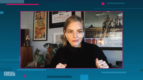 A Woman Wearing Ear Buds Stands In Front Of A Screen That Says Imdb On It GIF