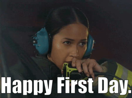 A Woman Wearing Ear Muffs Is Holding A Fire Extinguisher With The Words Happy First Day Below Her GIF