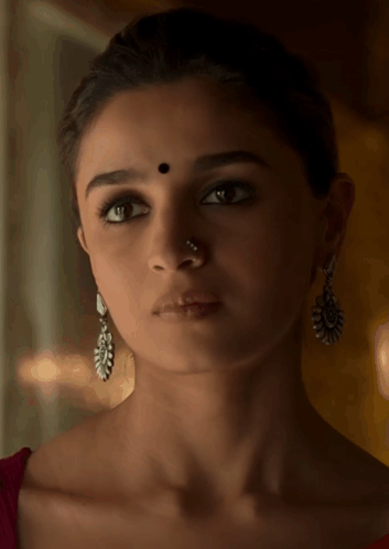 A Woman Wearing Earrings And A Nose Ring Has A Black Dot On Her Forehead GIF