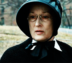 a woman wearing glasses and a black hat with a bow tie