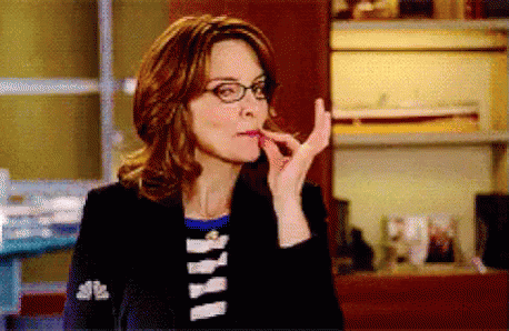 A Woman Wearing Glasses And A Black Jacket Is Eating Something . GIF