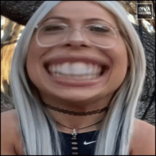 A Woman Wearing Glasses And A Choker Makes A Funny Face In Front Of Diva Digital GIF