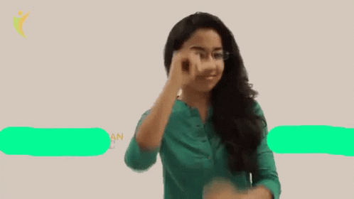 a woman wearing glasses and a green shirt points her finger up