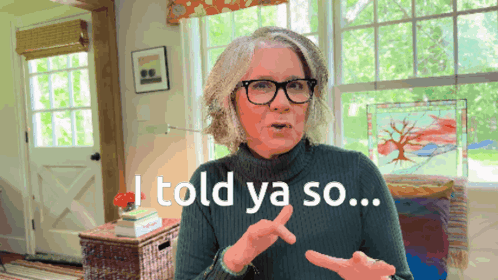 a woman wearing glasses and a green sweater says i told ya so