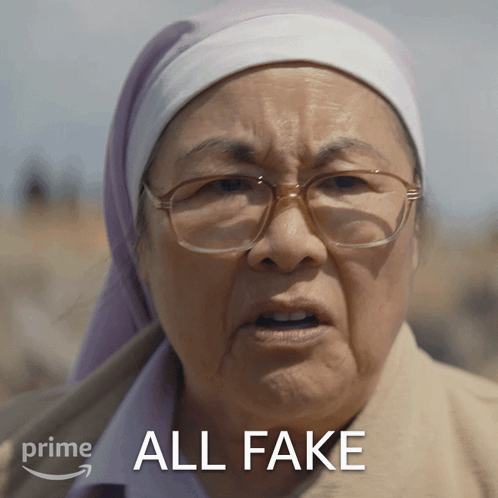 A Woman Wearing Glasses And A Head Scarf Has The Words All Fake Above Her GIF
