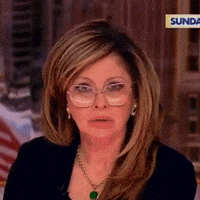 A Woman Wearing Glasses And A Necklace Is Sitting On A Sunday Show GIF