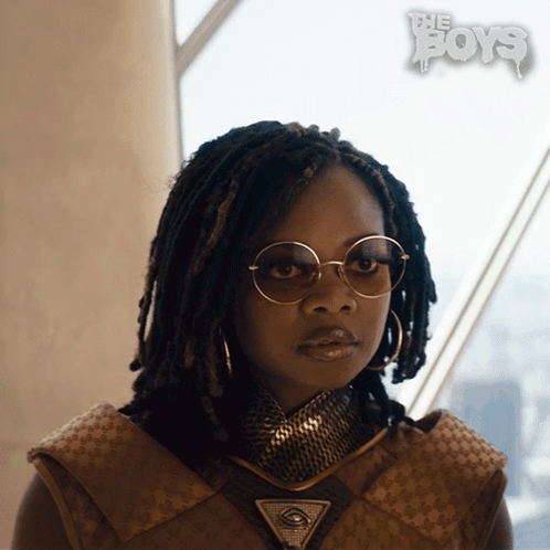 A Woman Wearing Glasses And A Necklace With The Boys Written On The Bottom Right GIF