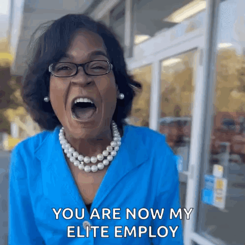 A Woman Wearing Glasses And A Pearl Necklace Is Screaming With Her Mouth Wide Open . GIF