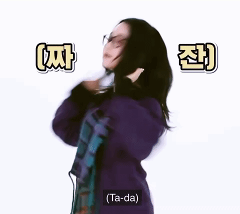 A Woman Wearing Glasses And A Purple Sweater Is Dancing And Says Ta-Da . GIF