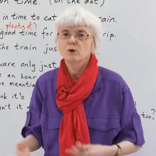 A Woman Wearing Glasses And A Red Scarf Stands In Front Of A White Board That Says " In Time To Cat " GIF