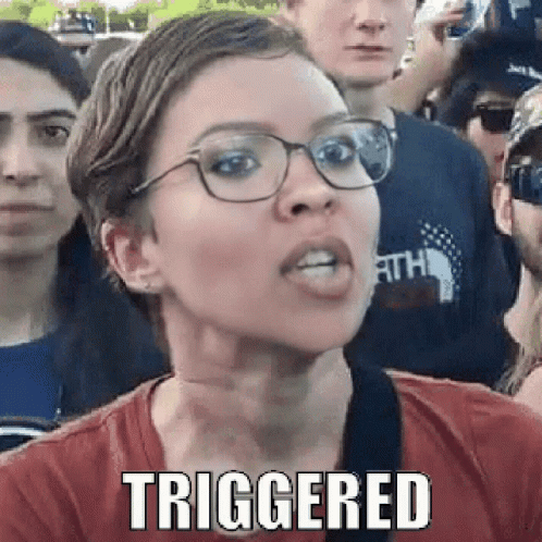 A Woman Wearing Glasses And A Red Shirt Is Making A Funny Face While Standing In Front Of A Crowd . GIF