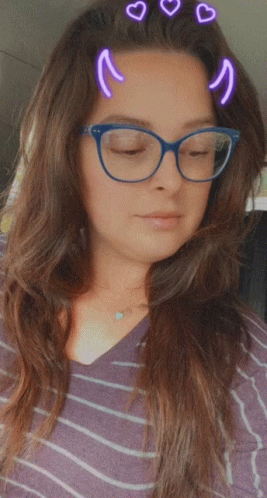 A Woman Wearing Glasses And A Striped Shirt Has Hearts On Her Hair GIF