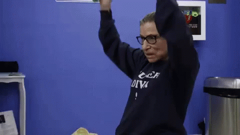 A Woman Wearing Glasses And A Sweatshirt That Says " Car Diva " Is Dancing In A Room . GIF
