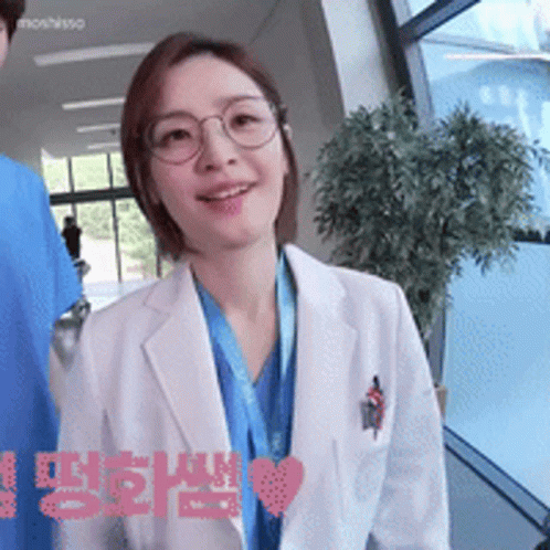 A Woman Wearing Glasses And A White Coat Has A Heart In The Corner GIF