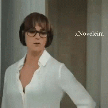 A Woman Wearing Glasses And A White Shirt Is Standing In Front Of A Door With Xnovelaira Written On The Bottom GIF