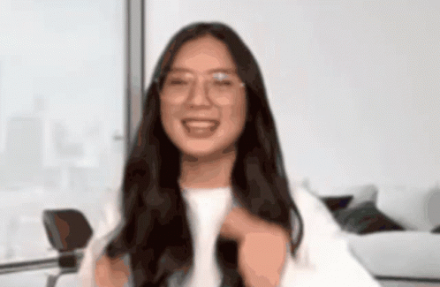 A Woman Wearing Glasses And A White Shirt Smiles For The Camera GIF