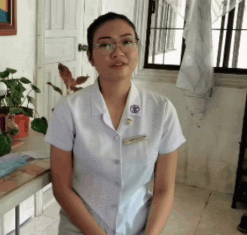 a woman wearing glasses and a white shirt with a name tag that says ' nurse ' on it