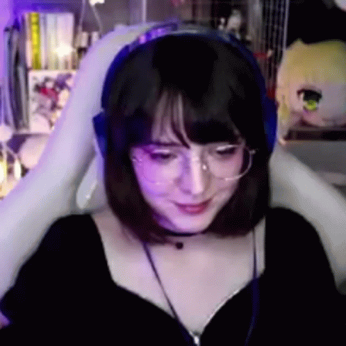 A Woman Wearing Glasses And Headphones Is Sitting In A Chair . GIF