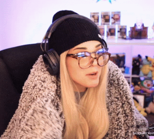 A Woman Wearing Glasses And Headphones Is Sitting In A Chair .. GIF