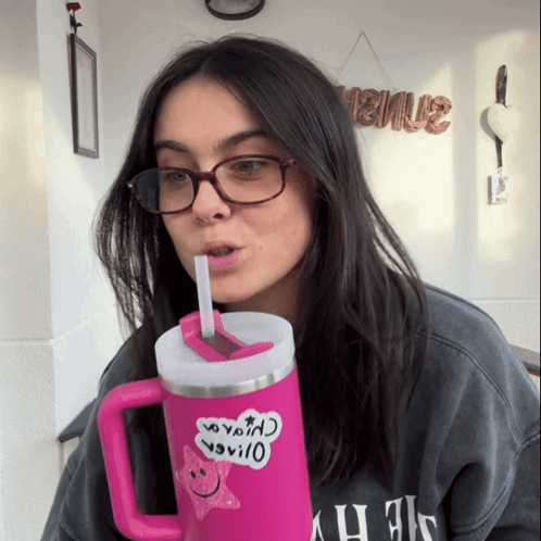 A Woman Wearing Glasses Is Drinking From A Pink Mug With A Sticker On It That Says " I Love You " On It GIF
