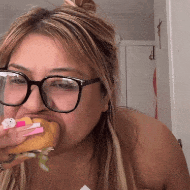 a woman wearing glasses is eating a hamburger with a hello kitty on it