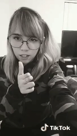 A Woman Wearing Glasses Is Giving A Thumbs Up Sign In A Black And White Photo . GIF