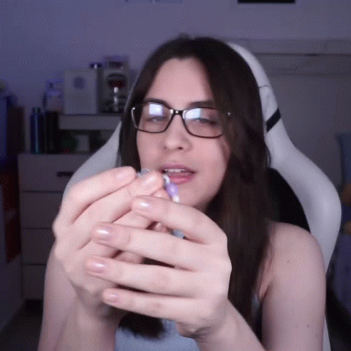 A Woman Wearing Glasses Is Holding A Blue Object In Her Hands GIF
