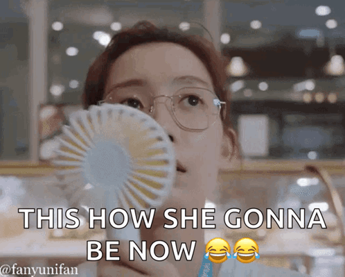 A Woman Wearing Glasses Is Holding A Fan In Her Mouth And Says This How She Gonna Be Now GIF
